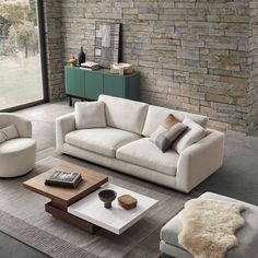 a living room filled with furniture and a brick wall behind the couches in front of a large window