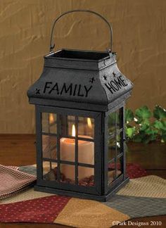 a lit candle sits on a table next to a potted plant and napkins