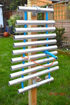 a wooden pole with several metal tubes attached to it in the grass next to a fence