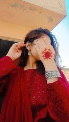 a woman with her hands on her face and hand covering her eyes while wearing a red dress