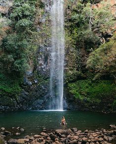 a person standing in the water under a waterfall