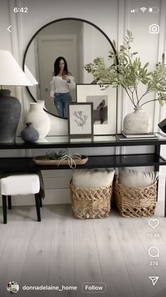 a woman taking a selfie in front of a mirror and table with vases on it