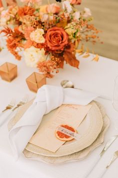 an elegant table setting with orange flowers and napkins