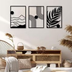 three black and white paintings hanging on the wall above a wooden dresser in a living room