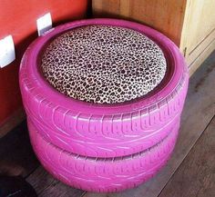 an orange tire shaped stool sitting on top of a wooden floor next to a red wall