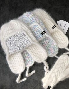 three white knitted mittens with sequins on the top and one in the middle