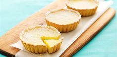 three small pies sitting on top of a wooden cutting board