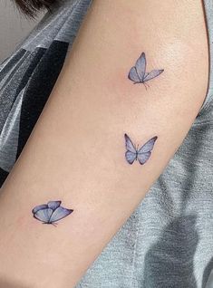 two blue butterflies on the left arm and one is in the middle of the arm