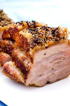 a piece of meat sitting on top of a white plate next to a blue napkin