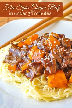 a white plate topped with pasta and meat covered in sauce next to chopsticks