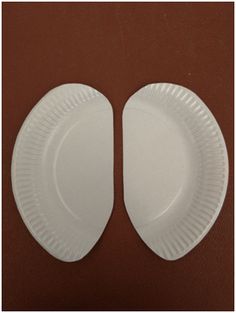 two white paper plates sitting side by side on a brown surface with one facing the camera