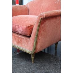 an old pink chair with gold trim on the armrests and foot rests against a wall