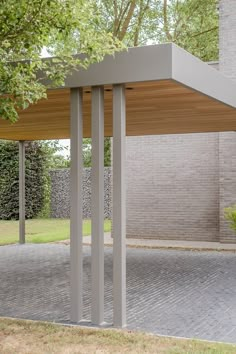 an outdoor covered area in front of a brick building with trees and grass around it