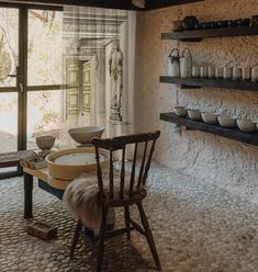 an old fashioned kitchen with stone walls and flooring, including a dining room table