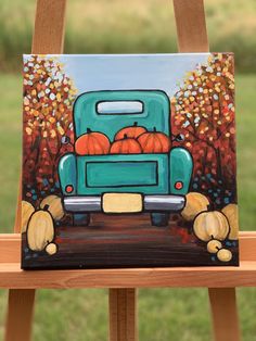 a painting of a truck with pumpkins in the back on a wooden easel