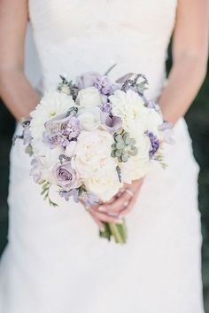 a bride holding a bouquet of white and purple flowers