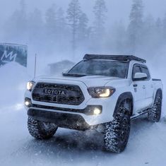 a white toyota truck driving through the snow