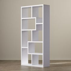 an empty white bookcase on the floor in front of a gray wall and wooden floors