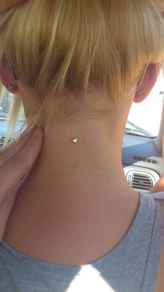 a woman in a car with her back to the camera, wearing a small diamond necklace