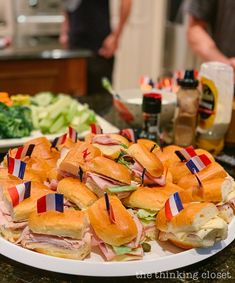 a plate full of sandwiches with flags on them