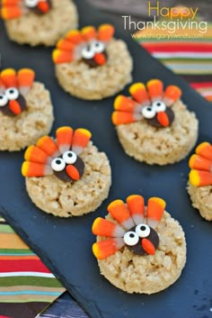 cookies decorated to look like turkeys are on a blue platter with candy eyes