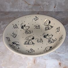 a bowl with peanuts on it sitting on a marble countertop next to a wall