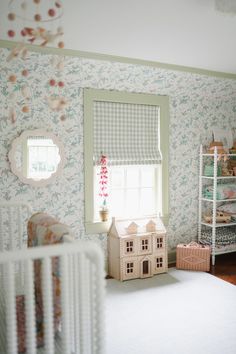 a baby's room with floral wallpaper and a doll house in the corner