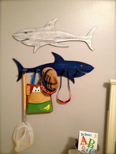 two fish hooks hang on the wall above a child's crib and hat rack