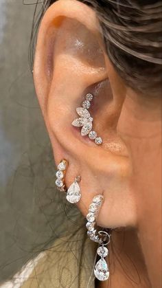 a close up of a person's ear with three different types of earrings on it