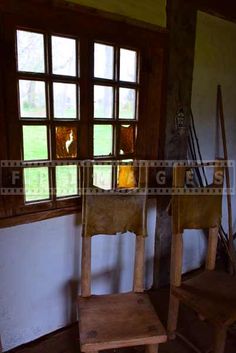 two wooden chairs sitting in front of a window