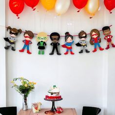 a birthday party with balloons and paper cutouts hanging from the ceiling over a table