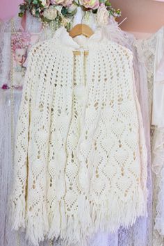 "Pre Loved Great Condition No Stains, Rips, or Snags Vintage 1970s Beautifully Handmade Beautiful cream crochet knit cape with a high neckline and front puff ball fringe tie closure..and fringe at the bottom..Can be paired with almost anything, such a cute statement piece to have.  High Neckline Puff Ball Fringe Tie Closure Abstract Design Fringe at Bottom Hem Cape/Poncho Boho/Hippie Style Material: Acrylic Soft and Comfortable One Size  Check the Measurements Below: Shoulder to Shoulder: Approx Vintage Cream Crochet Top With Crochet Trim, Vintage Cream Crochet Top With Trim, Vintage Cream Crochet Top, Vintage Beige Crochet Top With Crochet Trim, White Vintage Crochet Top For Festivals, Handmade Bohemian Crochet Top For Winter, Fringe Cape, Knitted Cape, Ladies Poncho