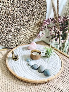 a small tray with rocks and a ring on it next to a wicker basket