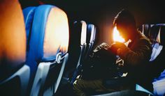 a man is sitting in an airplane and looking at his cell phone as the sun goes down