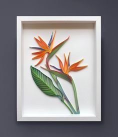 a white frame with some colorful flowers and leaves on the wall next to a gray wall