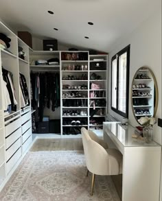 a walk in closet with white shelving and lots of shoes