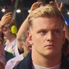 a man with blonde hair wearing a bow tie in front of a group of people