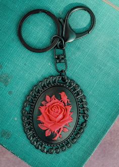 a pair of black scissors sitting on top of a green book with a red rose in the center