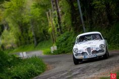 an old white car driving down a country road