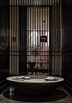 a round bathtub in the middle of a room with bars on either side and flowers growing out of it