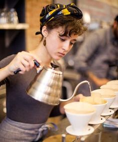 a woman pours coffee into cups at a cafe