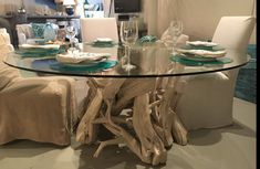 a glass table with driftwood pieces on top and white chairs around it in a living room