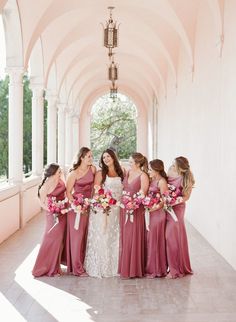 a group of women standing next to each other holding bouquets in front of a building