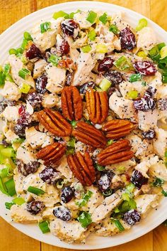 a white plate topped with chicken salad and pecans on top of a wooden table