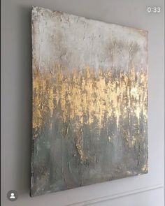 a painting hanging on the wall in a living room with white and gold paint over it