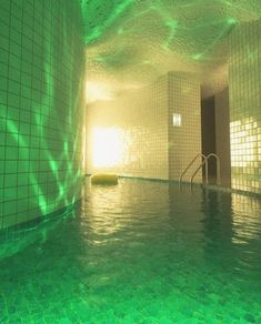 an indoor swimming pool with green tile walls