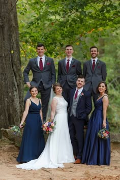 a group of people standing next to each other in front of some trees and bushes