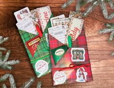 some christmas cards are laying on top of a wooden table next to evergreen branches and pine cones