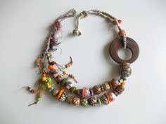 a necklace made with beads and other items on a white surface, including a wooden ring