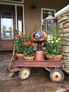 a wagon filled with potted plants sitting on top of a wooden floor next to a building